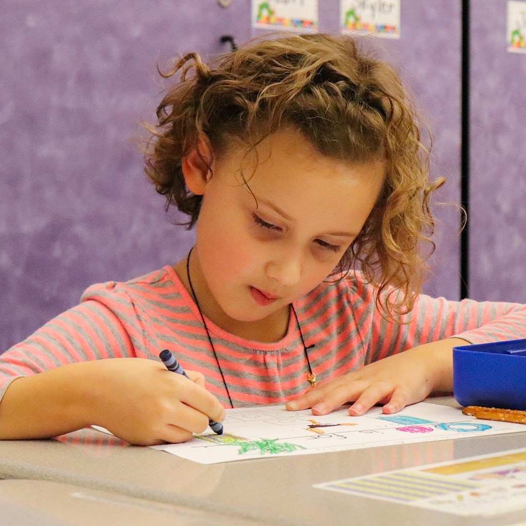 Young girl coloring with crayon