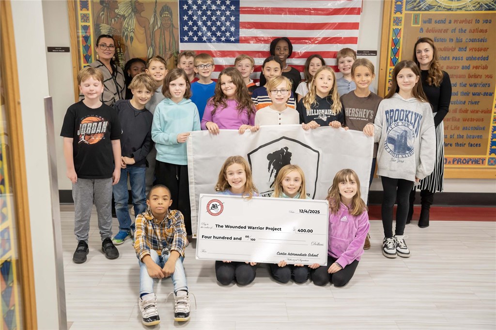 Students gather around a check made out to The Wounded Warrior Project.