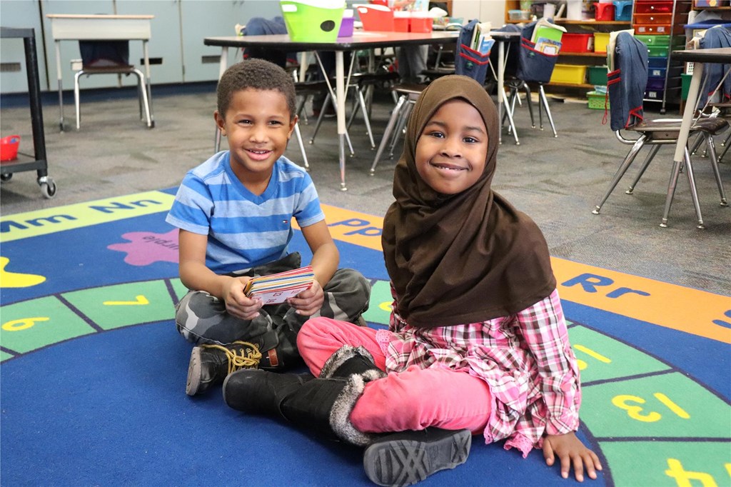 Two children sitting on rug in classroom
