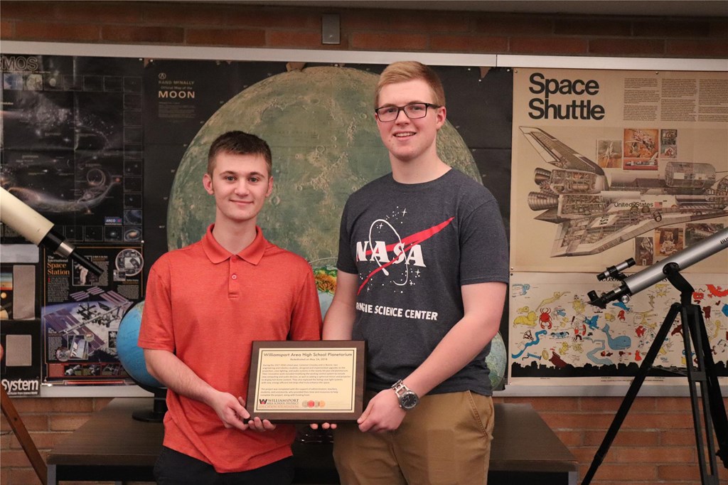 Two students holding plaque