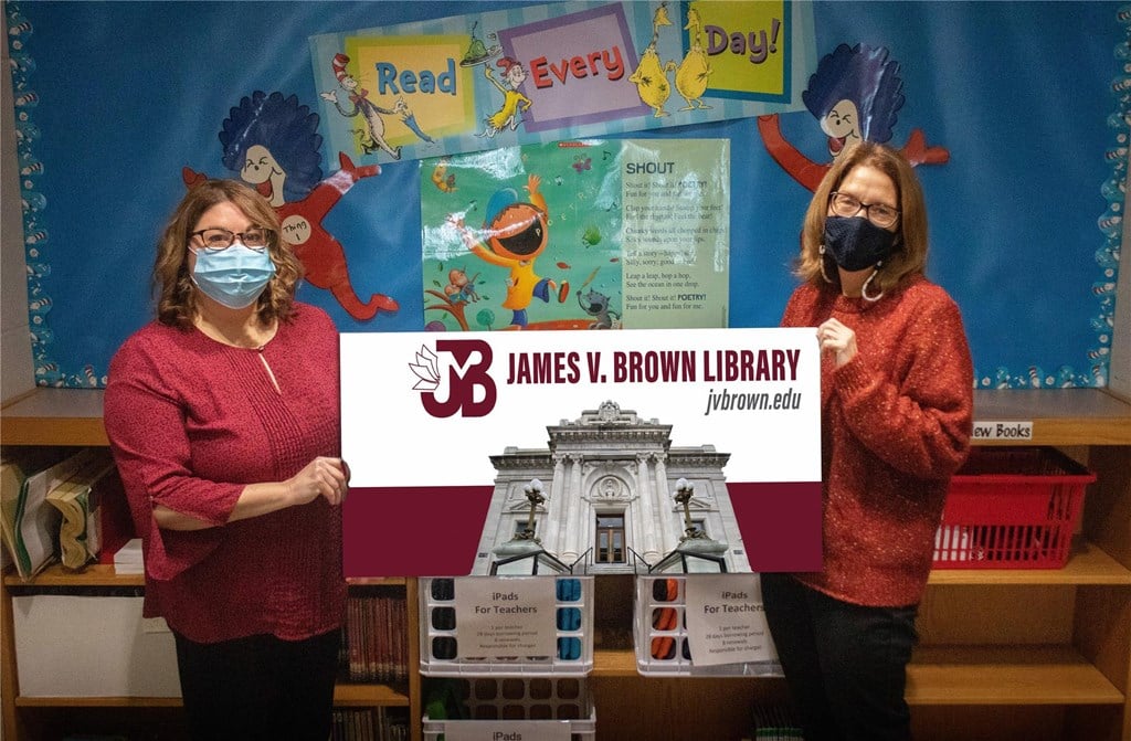 Barbara McGary and Sarah Bohnert hold a giant library card.