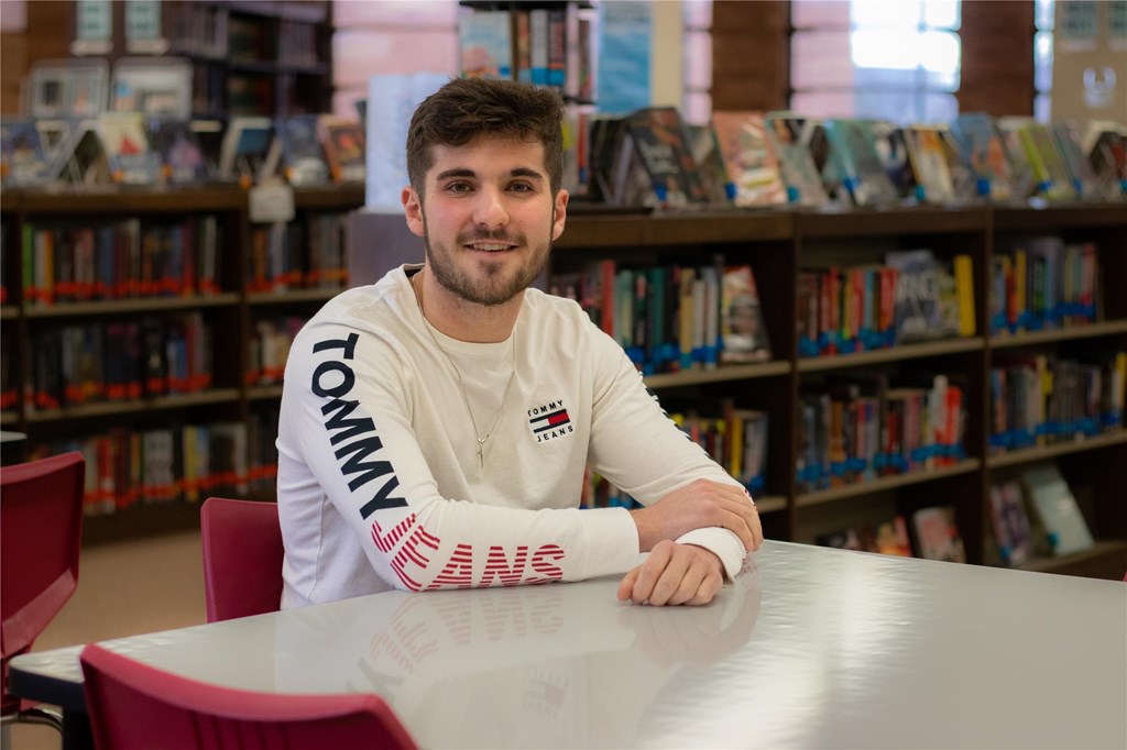 Ben Manetta poses at a table in the high school library.